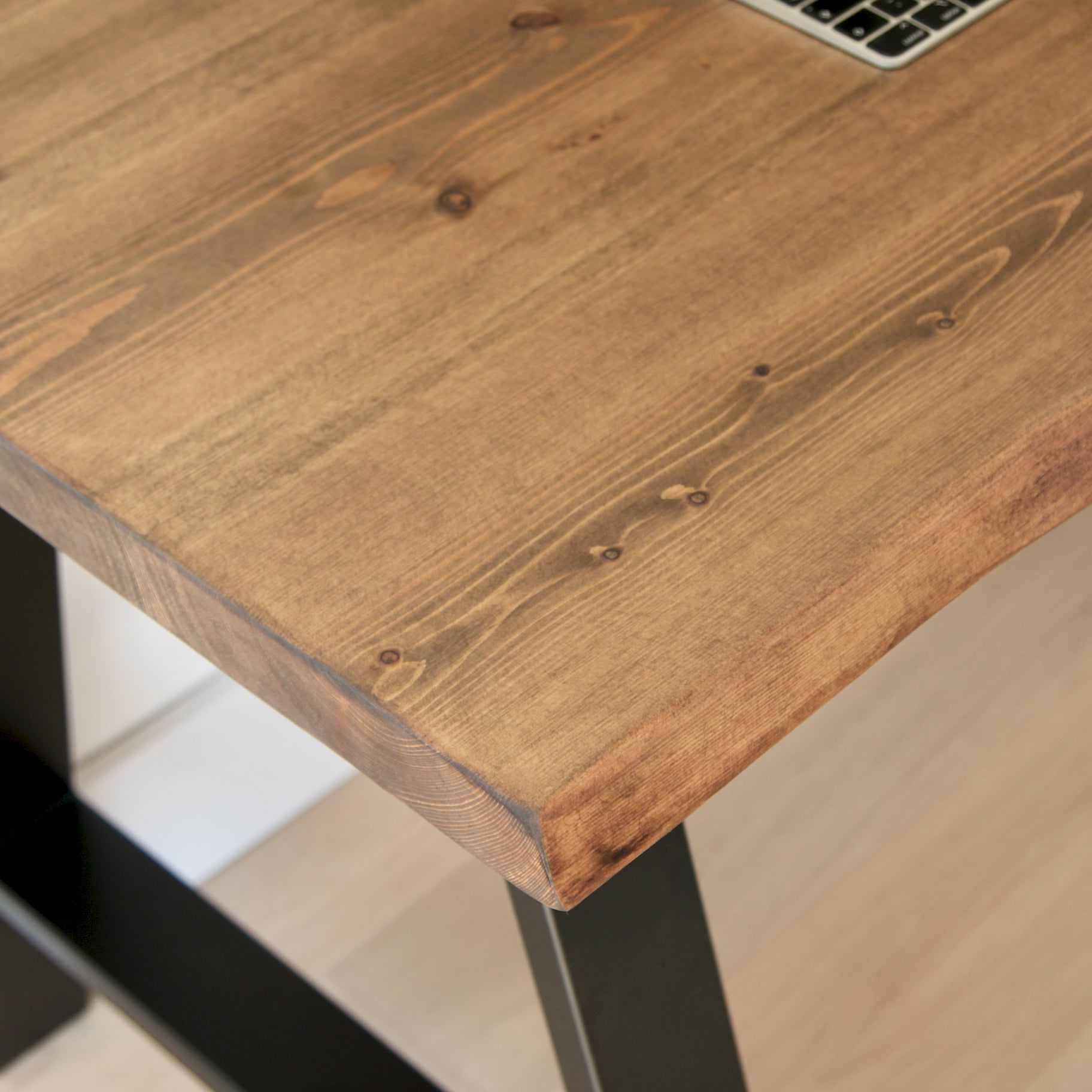 Wooden desk with a laptop on top, close-up view