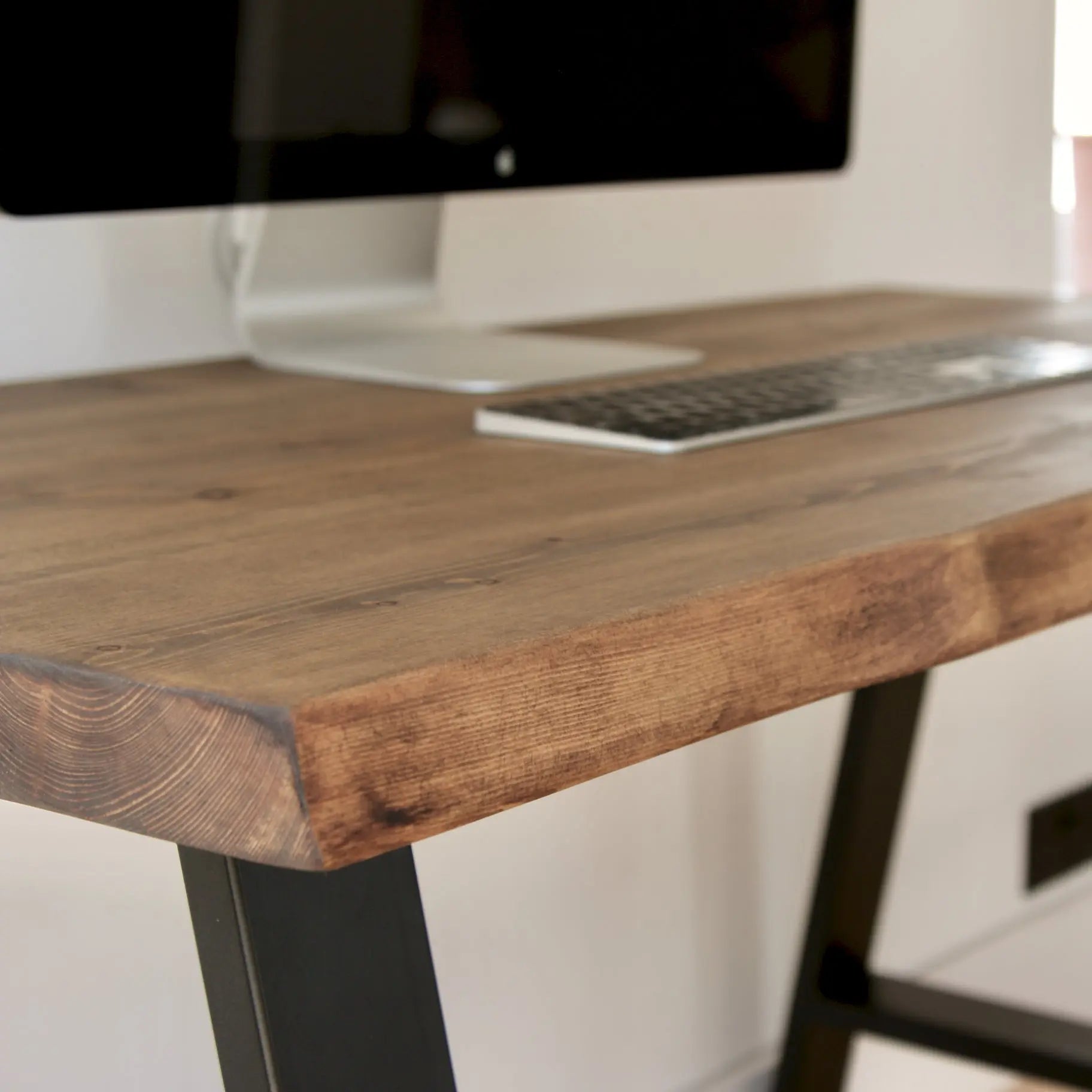 Wooden desk with computer monitor and keyboard on a blurred background