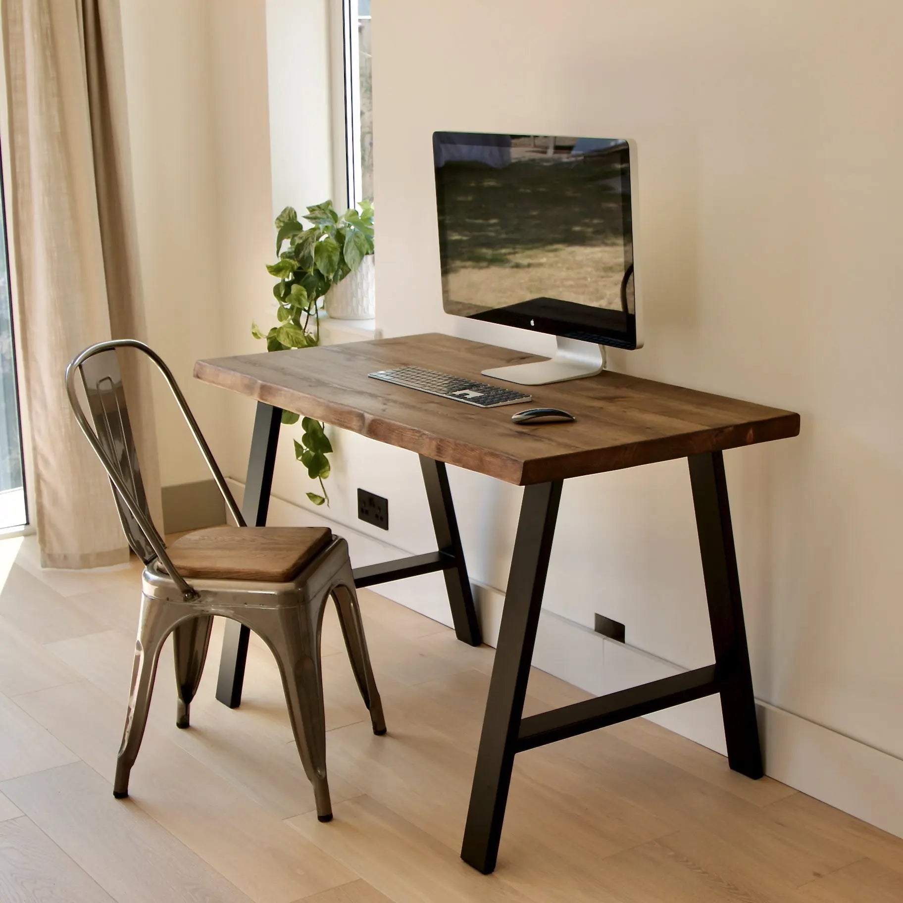 Wooden desk with chair in a room with a window and plant