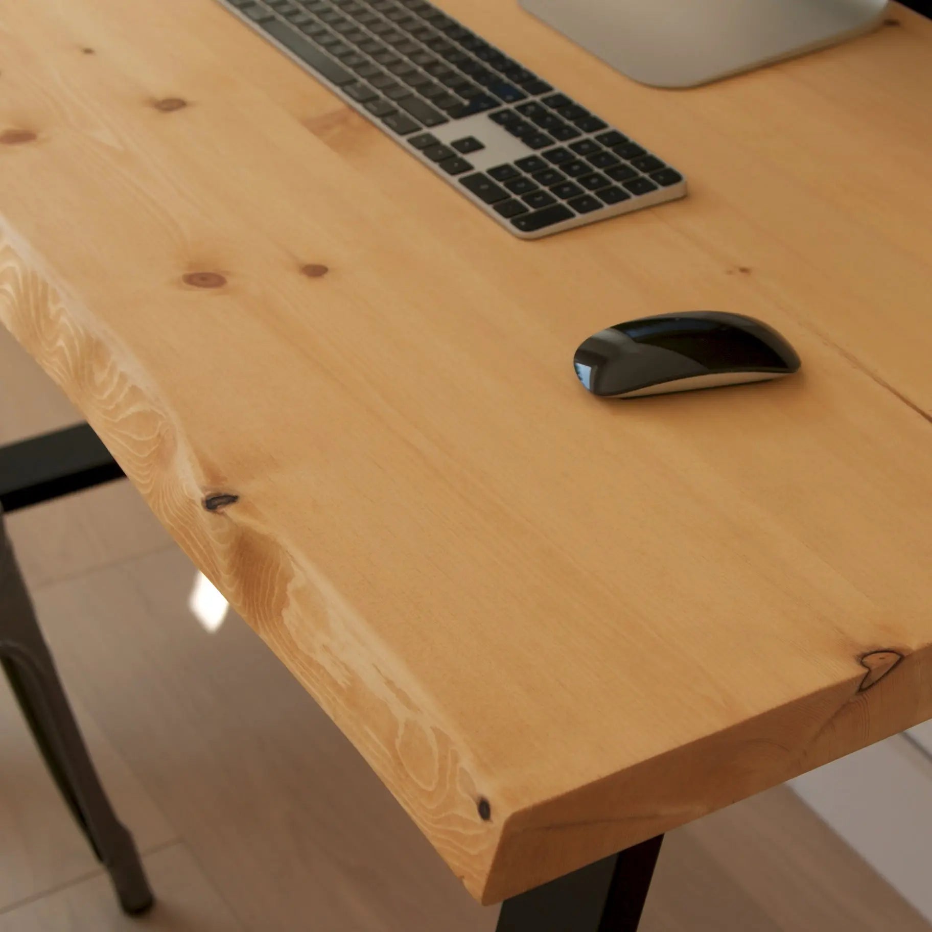 Wooden desk with a laptop, keyboard, and mouse on a blurred background