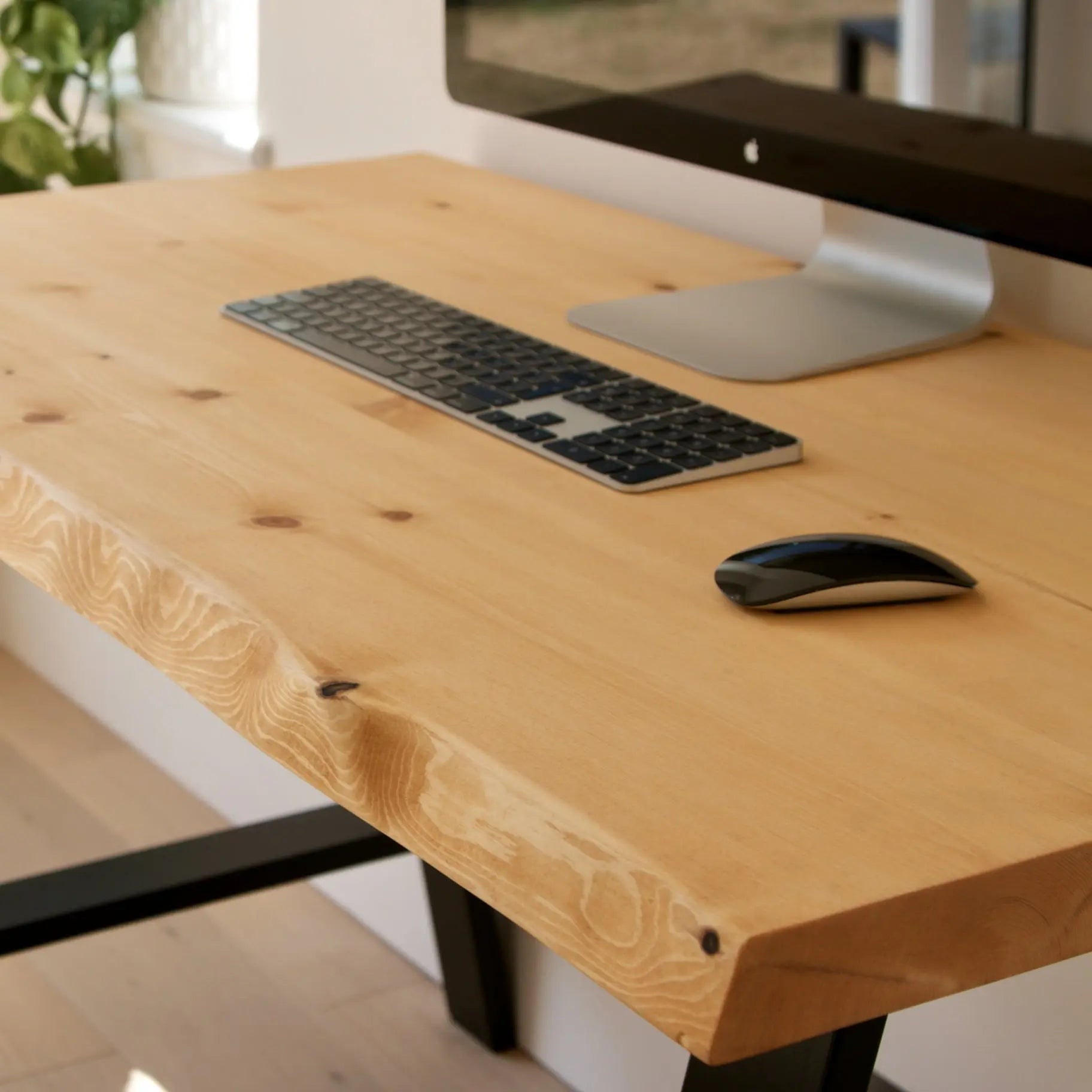 Wooden desk with computer keyboard and mouse on a blurred indoor background