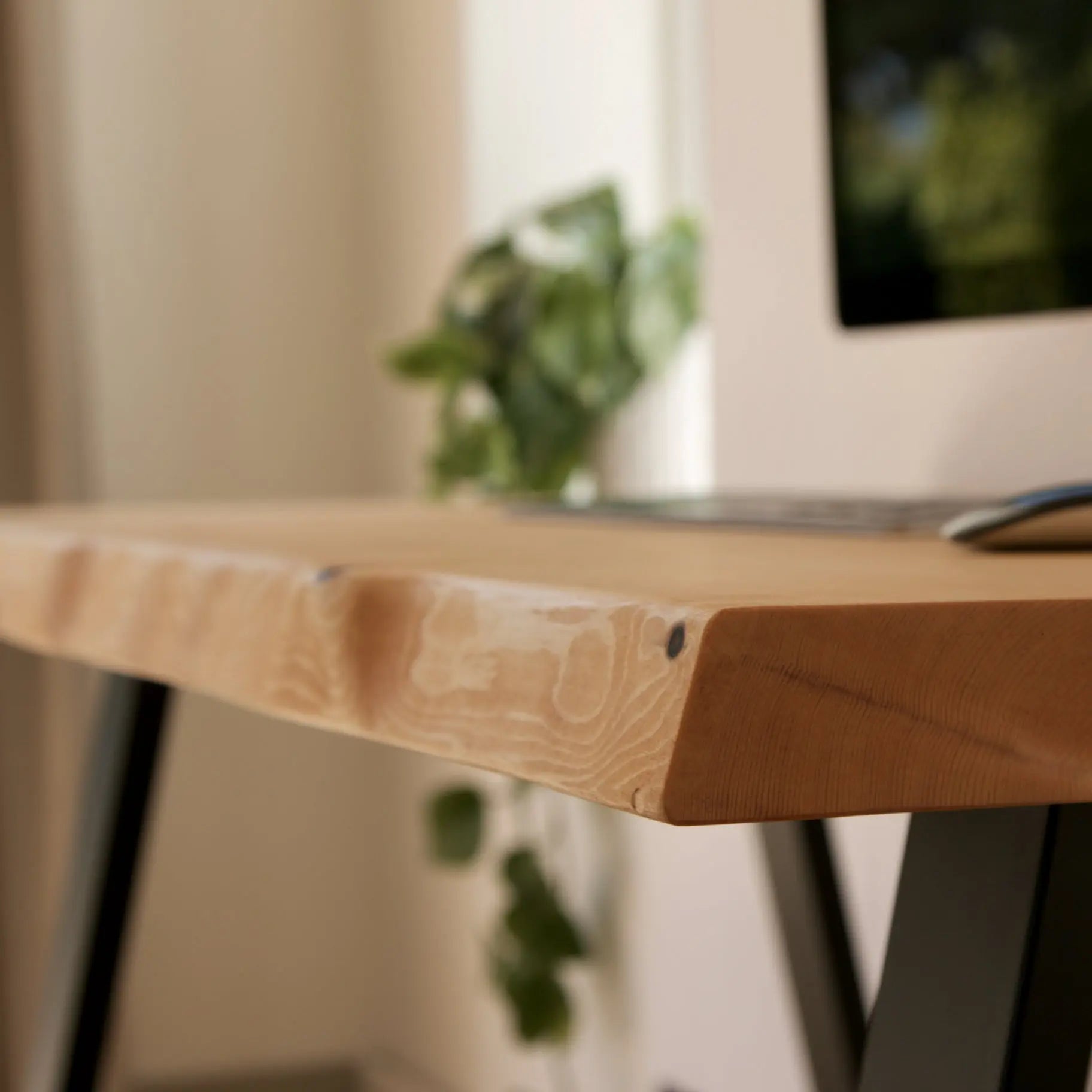 Wooden desk with a laptop and mouse on a blurred indoor background