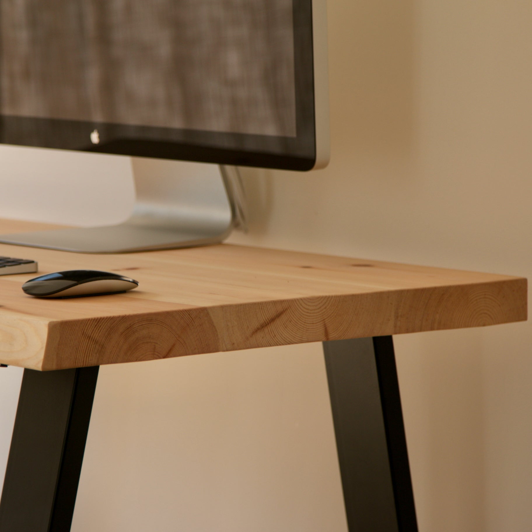 Wooden desk with computer monitor and mouse on a neutral background