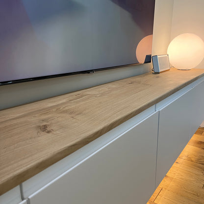Modern interior with a television mounted on a wall above a wooden oak shelf.