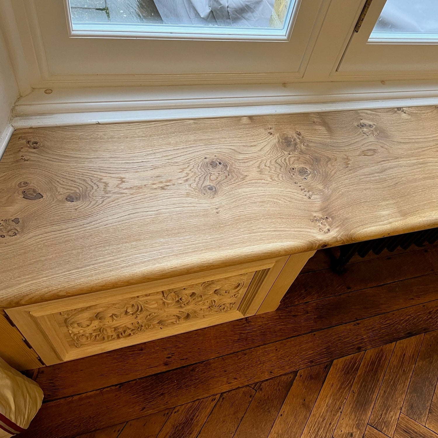 Wooden oak bench with intricate carvings on a wooden floor.